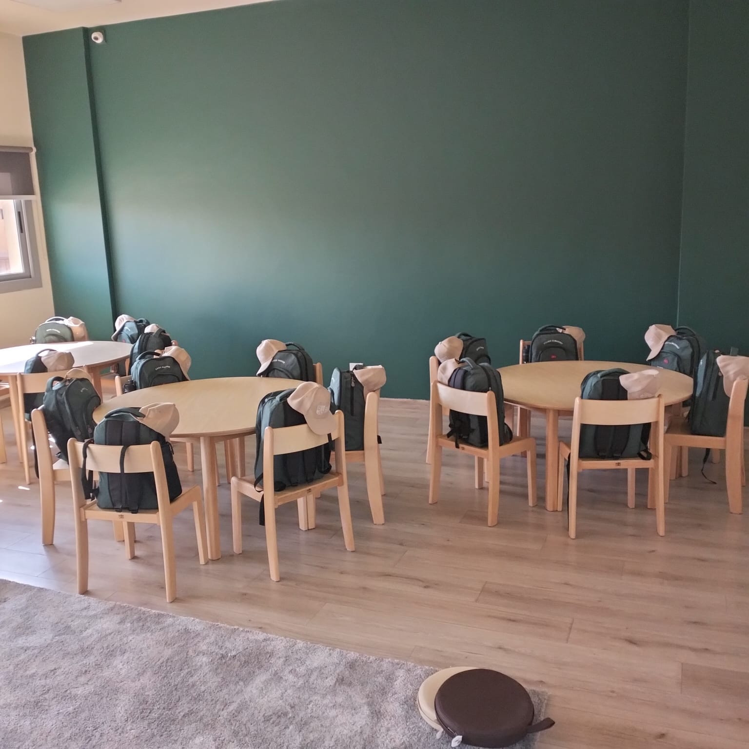 An ESE classroom with green walls and round activity tables