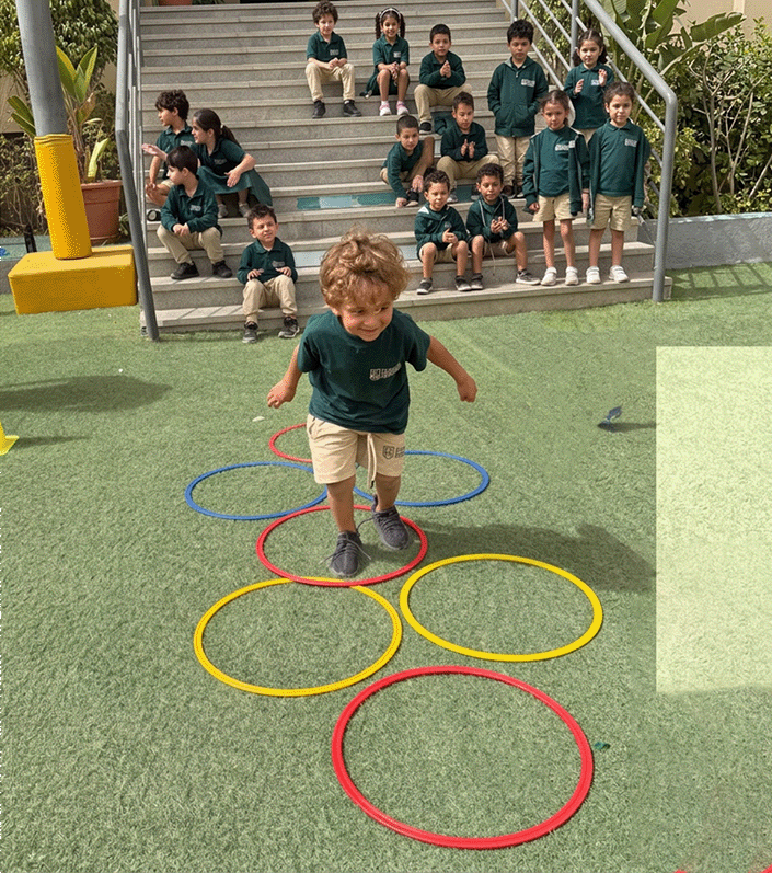 A student stepping through colourful outdoor hoops while classmates watch