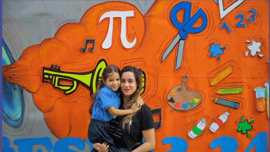 A child and adult together beside a colourful school activity display